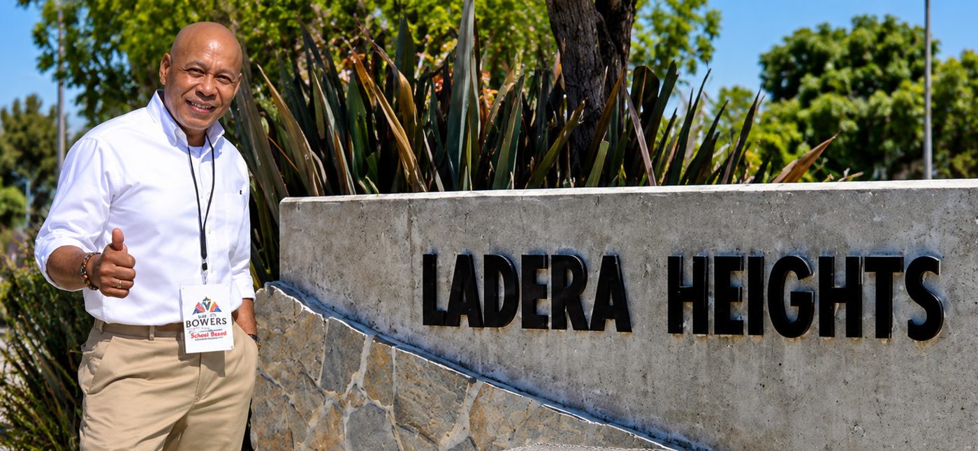 Joe Bowers giving a thumbs up beside the Ladera Heights sign